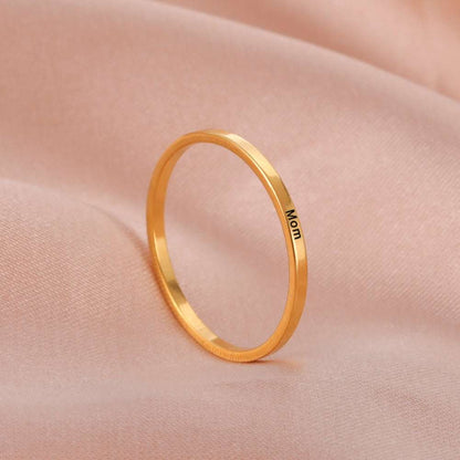 Custom engraved gold ring on soft fabric background.