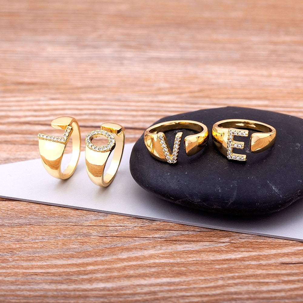 Wide YourLetter Initial Ring with cubic zirconia gems on wooden background.