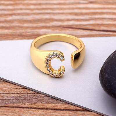 Wide YourLetter Initial Ring with cubic zirconia gems on a wooden surface.