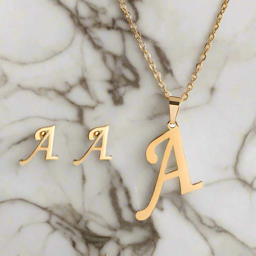 Yourletter Necklace & Earring Set in gold with initial "A" design on marble background.