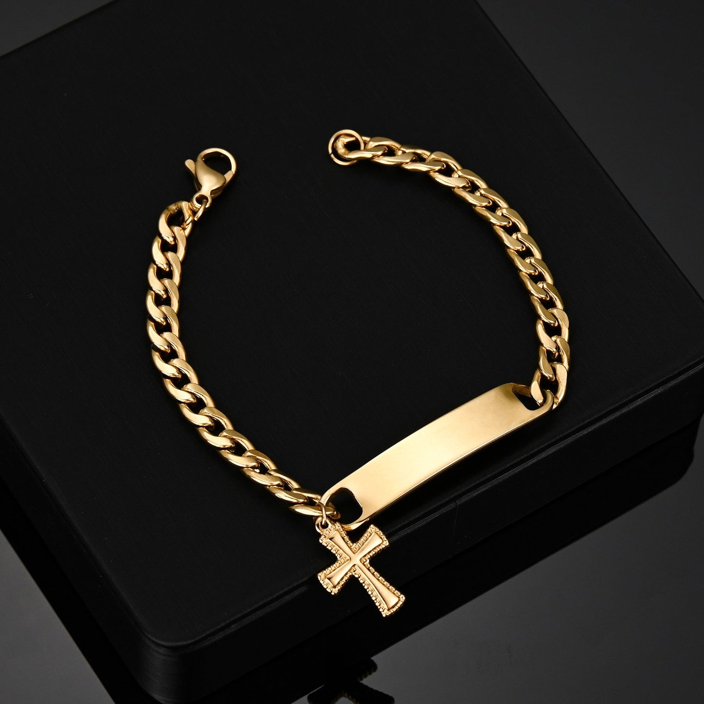 Engraved nameplate bracelet Cuban chain with cross pendant in gold.