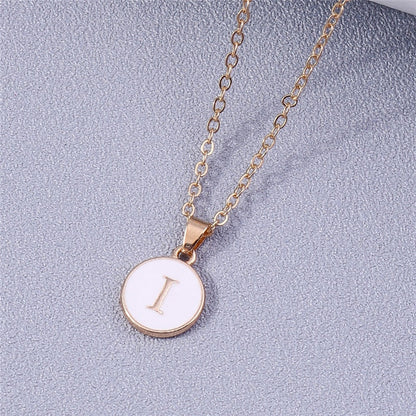 White enamel circle necklace with letter pendant and gold detailing.