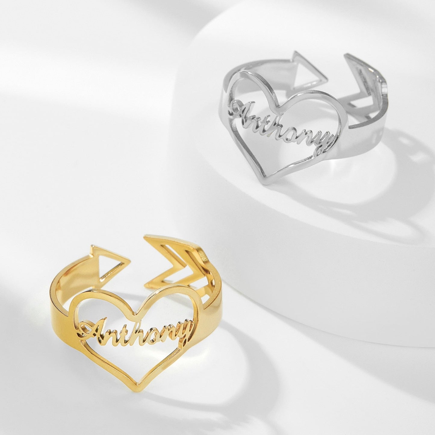 Customizable heart arrow ring in gold and silver, featuring name engraving and adjustable size.