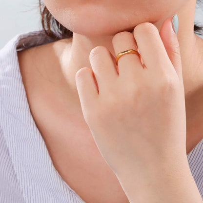 Engraved custom name flat band ring in gold finish on a woman's hand.