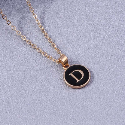 YourLetter Black Enamel Necklace with gold chain and letter pendant on black background.