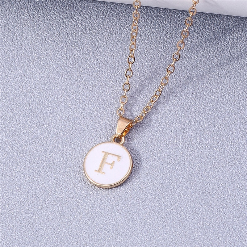 Custom white enamel circle necklace with gold detailing and letter pendant.