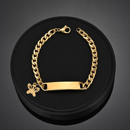 Engraved nameplate bracelet on Cuban chain with butterfly pendant in gold.